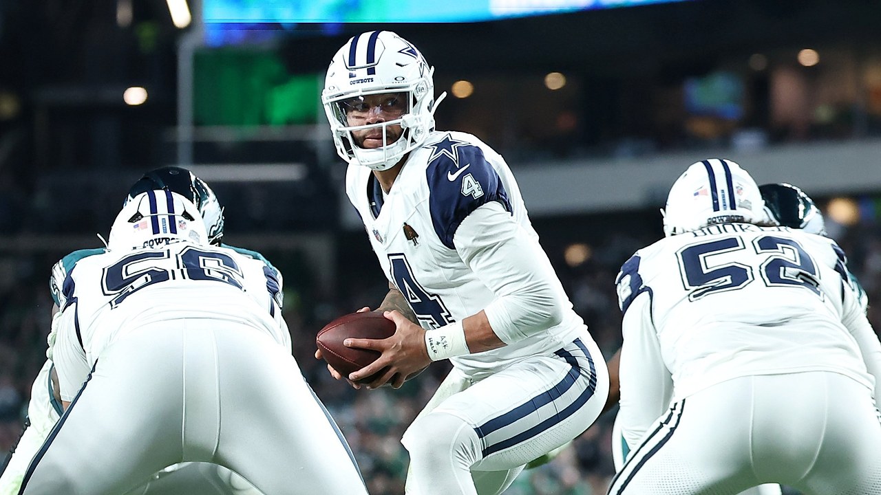 Dallas Cowboys quarterback Dak Prescott turns with the ball in both hands as his offensive linemen block in front of him.