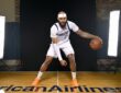 Dallas Mavericks forward/center Daniel Gafford dribbles a basketball in a low stance on the American Airlines Center logo.