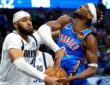Dallas Mavericks forward Daniel Gafford swipes at the ball as Oklahoma City Thunder guard Shai Gilgeous-Alexander grimaces on contact.