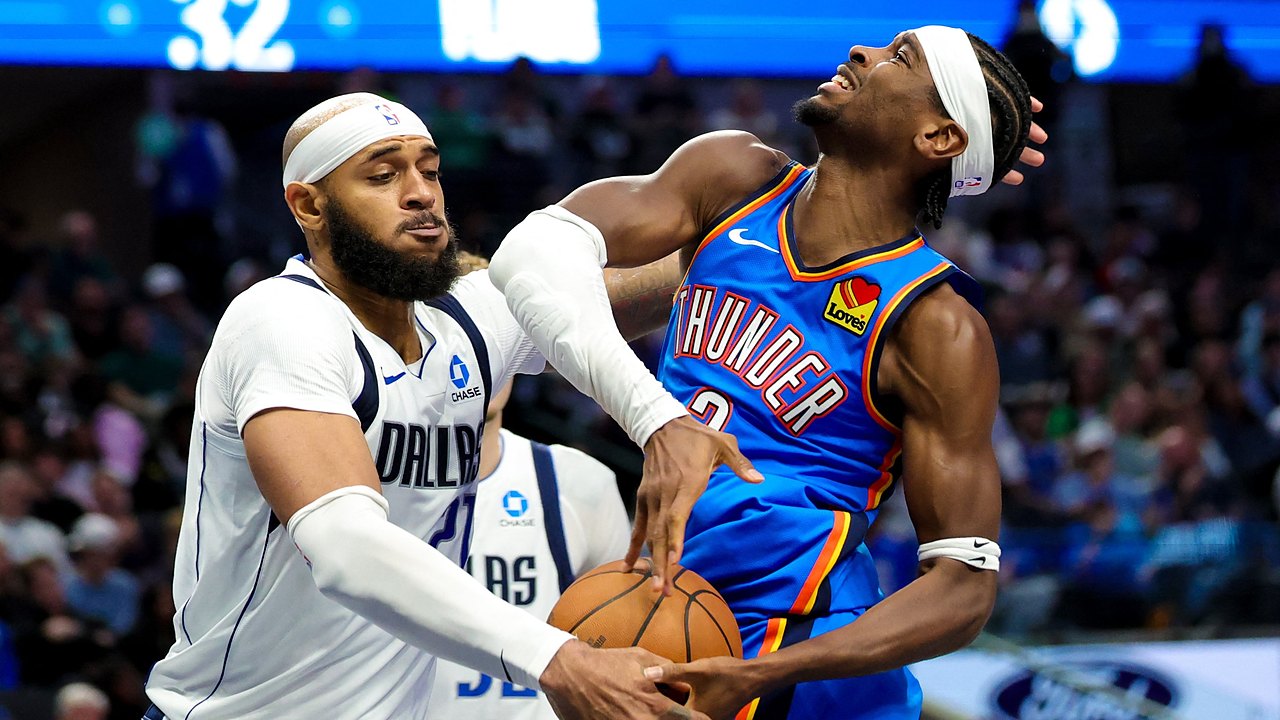 Dallas Mavericks forward Daniel Gafford swipes at the ball as Oklahoma City Thunder guard Shai Gilgeous-Alexander grimaces on contact.