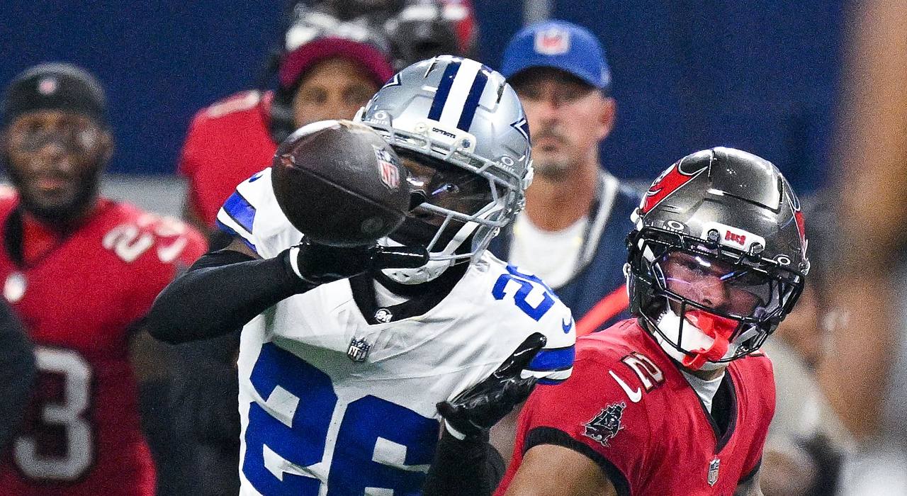 Cowboys cornerback DaRon Bland reaches for the ball with one hand as Buccaneers receiver Emeka Egbuka watches.