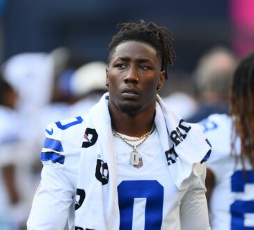 Cowboys linebacker DeMarvion Overshown, a towel draped around his neck, walks along the sideline in his white No. 0 jersey.