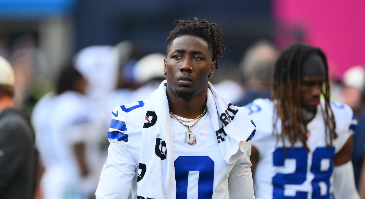 Cowboys linebacker DeMarvion Overshown, a towel draped around his neck, walks along the sideline in his white No. 0 jersey.