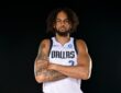 Dallas Mavericks center Dereck Lively II stands with his tattooed arms crossed in a white Dallas No. 2 jersey.