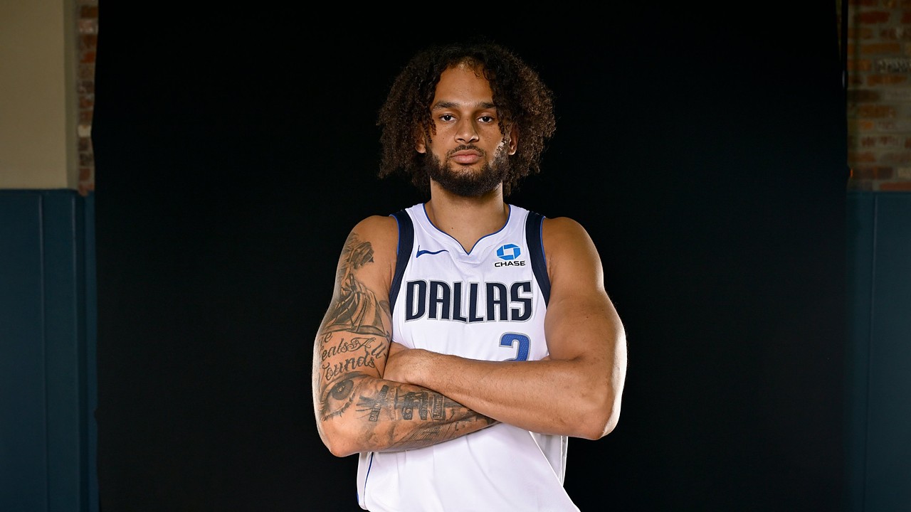 Dallas Mavericks center Dereck Lively II stands with his tattooed arms crossed in a white Dallas No. 2 jersey.