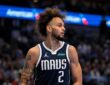 Dallas Mavericks center Dereck Lively II glances to his left while holding the ball in a navy MAVS jersey.