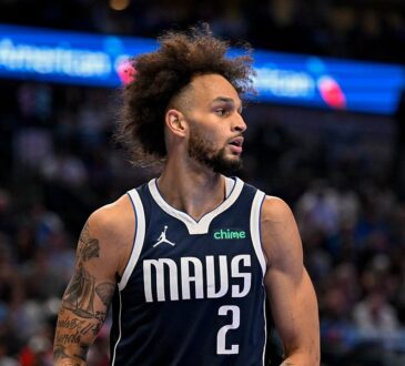 Dallas Mavericks center Dereck Lively II glances to his left while holding the ball in a navy MAVS jersey.