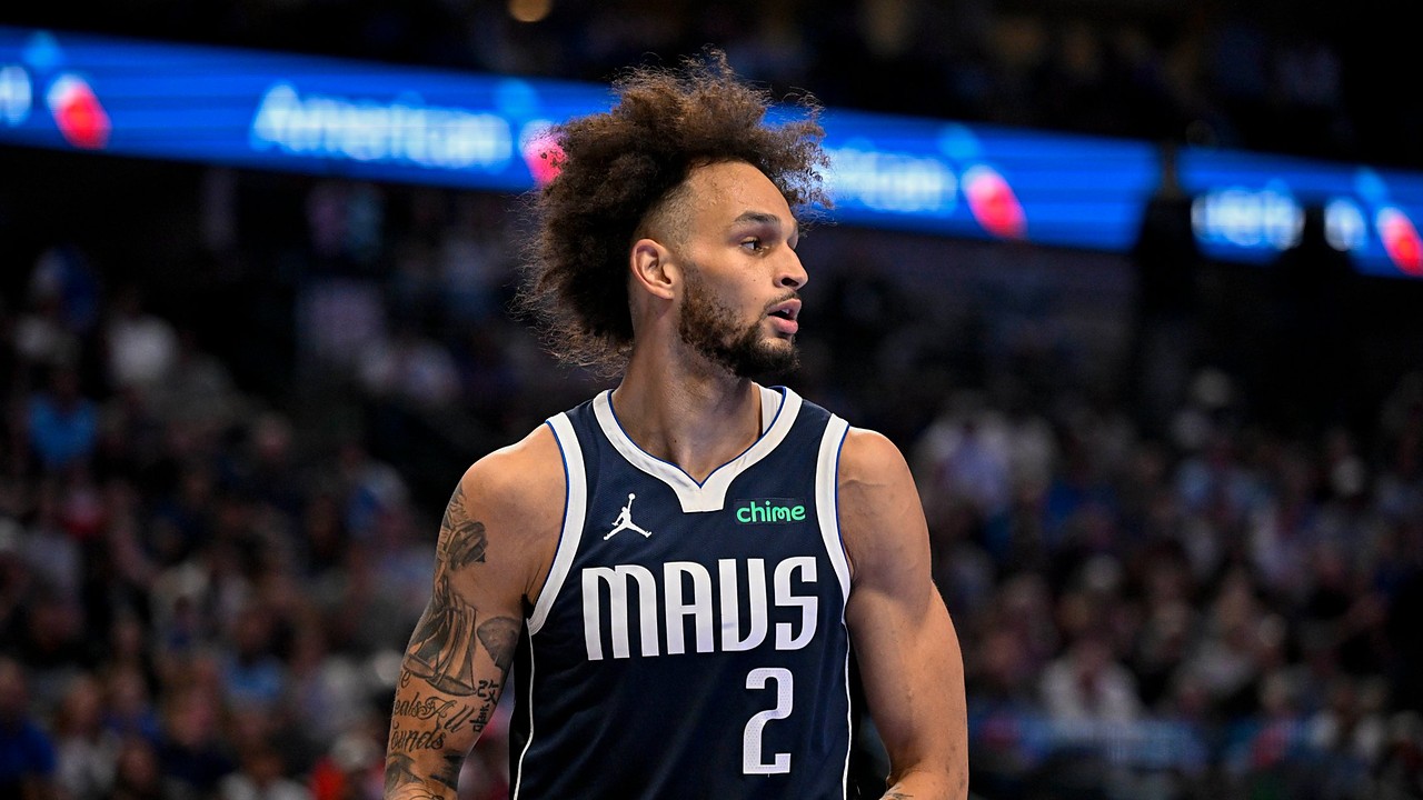 Dallas Mavericks center Dereck Lively II glances to his left while holding the ball in a navy MAVS jersey.