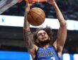 Dallas Mavericks center Dereck Lively II hangs on the rim with both hands after a two-handed dunk.