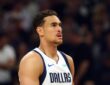 Dallas Mavericks forward Dwight Powell stands on the court looking toward the action in a white Dallas jersey.