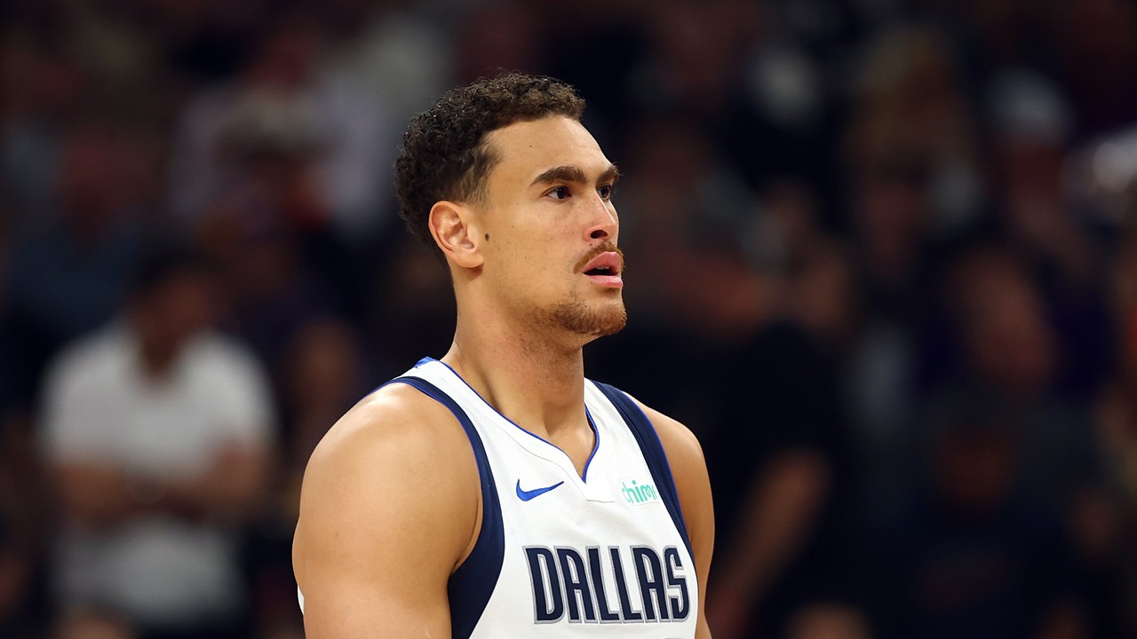 Dallas Mavericks forward Dwight Powell stands on the court looking toward the action in a white Dallas jersey.