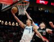 Dallas Mavericks forward Dwight Powell lays the ball up at the rim as Portland Trail Blazers center Donovan Clingan reaches to contest.