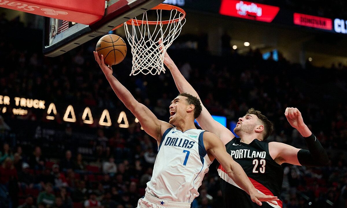 Dallas Mavericks forward Dwight Powell lays the ball up at the rim as Portland Trail Blazers center Donovan Clingan reaches to contest.