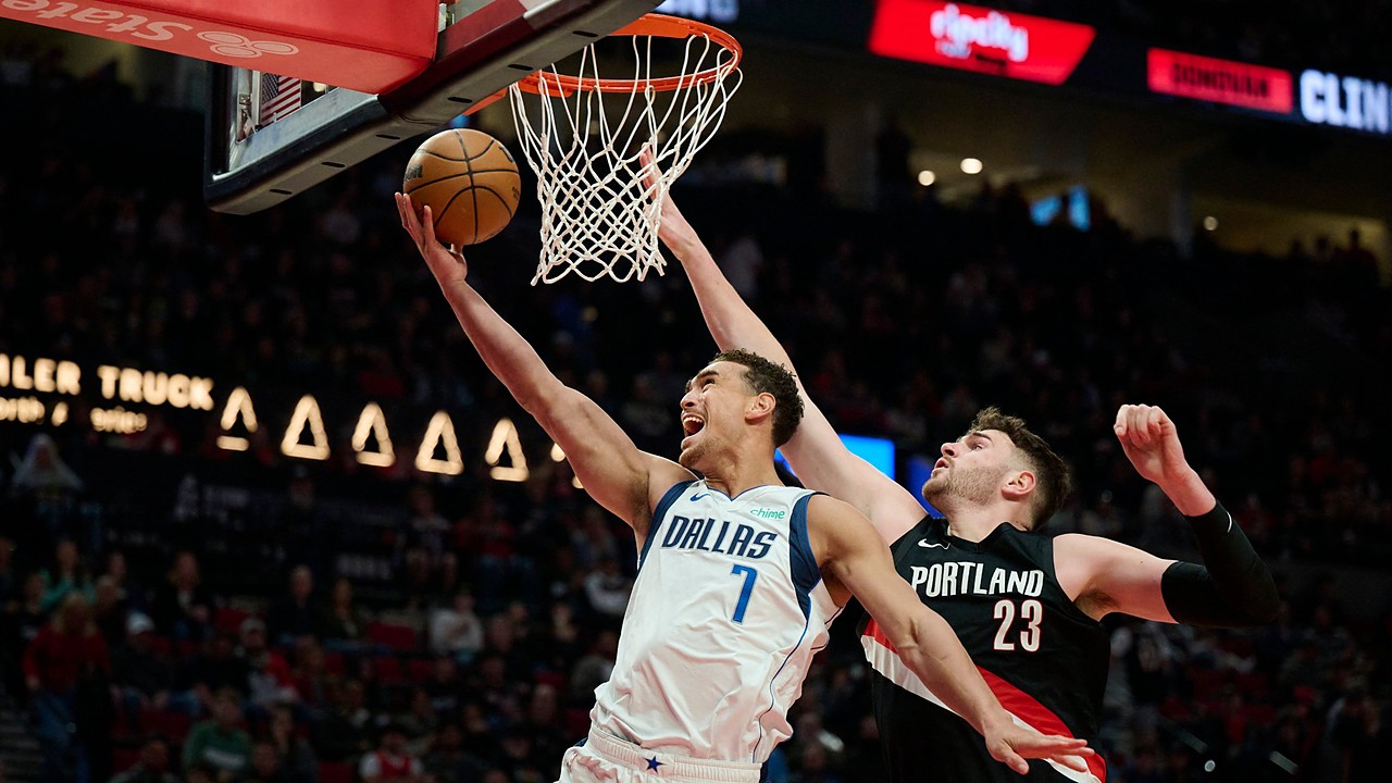 Dallas Mavericks forward Dwight Powell lays the ball up at the rim as Portland Trail Blazers center Donovan Clingan reaches to contest.