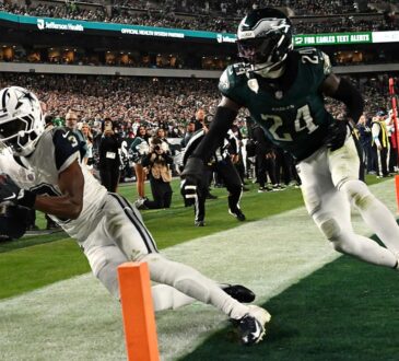 Dallas Cowboys wide receiver George Pickens dives to secure a touchdown catch at the pylon as an Eagles safety closes in.