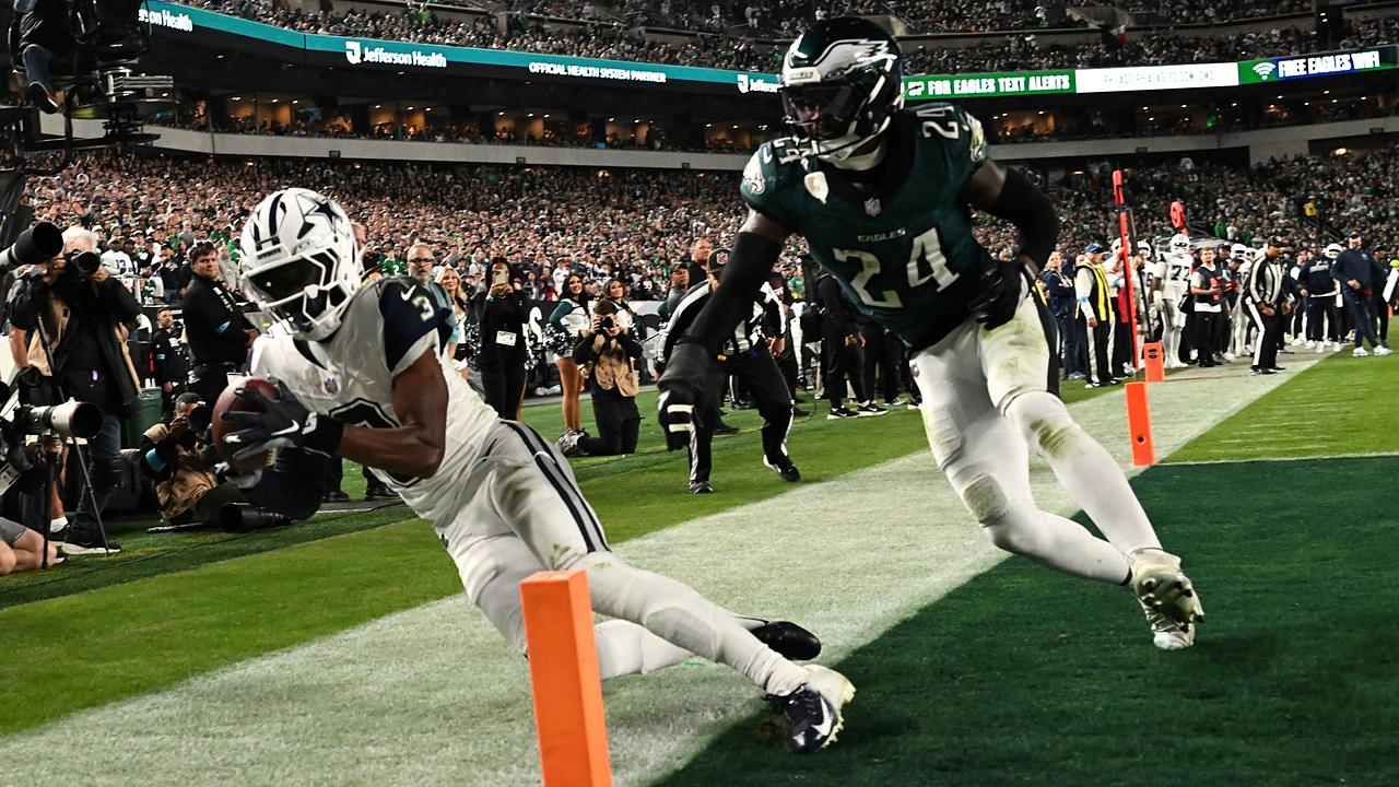 Dallas Cowboys wide receiver George Pickens dives to secure a touchdown catch at the pylon as an Eagles safety closes in.