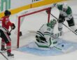 Dallas Stars goaltender Jake Oettinger drops to his knees to block a puck in the crease as Blackhawks and Stars players close in.