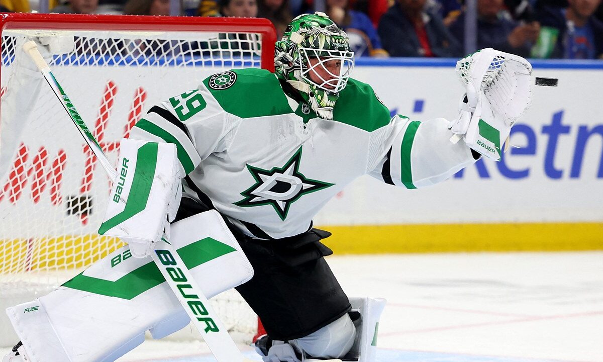 Dallas Stars goaltender Jake Oettinger reaches out with his glove to snag a puck in front of the net.