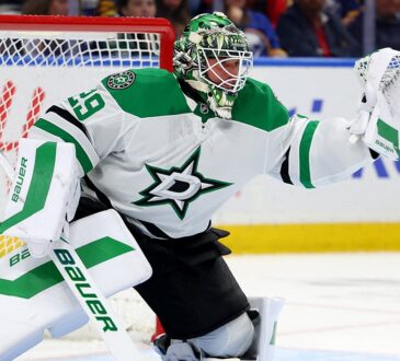 Dallas Stars goaltender Jake Oettinger reaches out with his glove to snag a puck in front of the net.