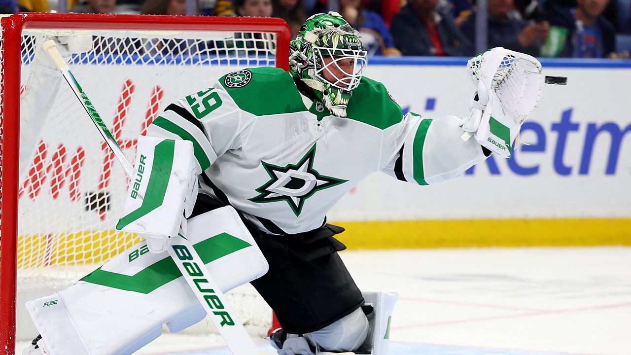 Dallas Stars goaltender Jake Oettinger reaches out with his glove to snag a puck in front of the net.