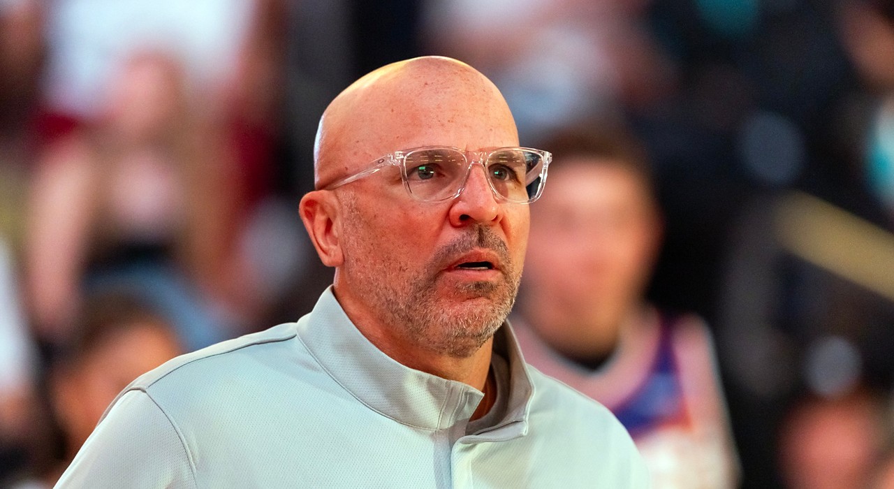 Then-Mavericks head coach Jason Kidd, wearing clear-framed glasses, looks on from the sideline with fans behind him.