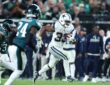 Dallas Cowboys running back Javonte Williams breaks into the open field with the ball as Eagles defenders chase.