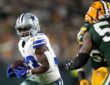 Dallas Cowboys running back Javonte Williams cradles the ball with both hands as a Green Bay Packers defender closes in.