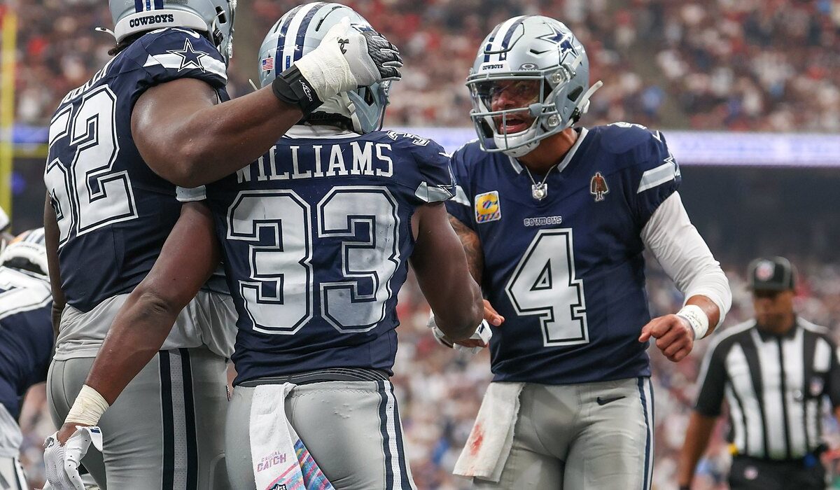Cowboys quarterback Dak Prescott shouts as he greets running back Javonte Williams while a lineman pats Williams’ helmet.