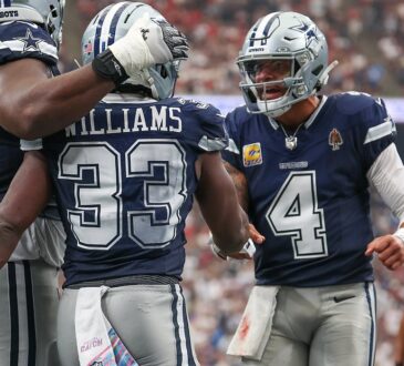 Cowboys quarterback Dak Prescott shouts as he greets running back Javonte Williams while a lineman pats Williams’ helmet.