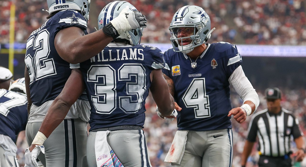 Cowboys quarterback Dak Prescott shouts as he greets running back Javonte Williams while a lineman pats Williams’ helmet.