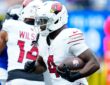 Arizona Cardinals running back Jeremiyah Love tucks the ball under his right arm as he runs upfield past a teammate.