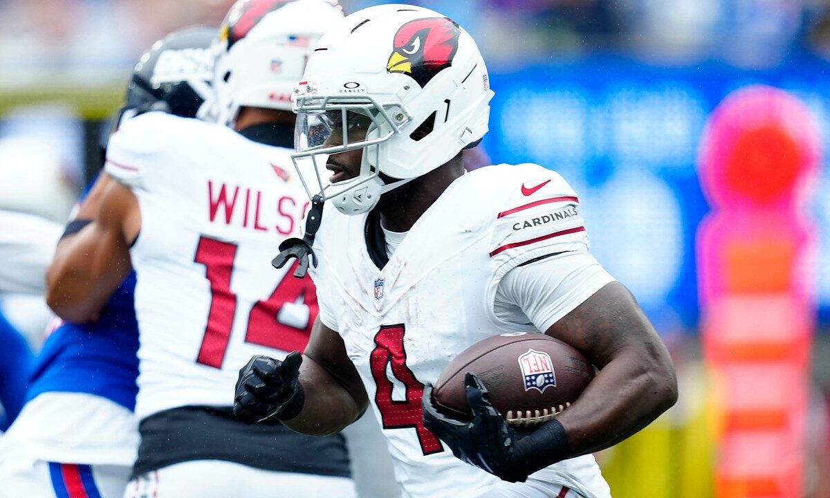 Arizona Cardinals running back Jeremiyah Love tucks the ball under his right arm as he runs upfield past a teammate.