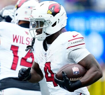 Arizona Cardinals running back Jeremiyah Love tucks the ball under his right arm as he runs upfield past a teammate.