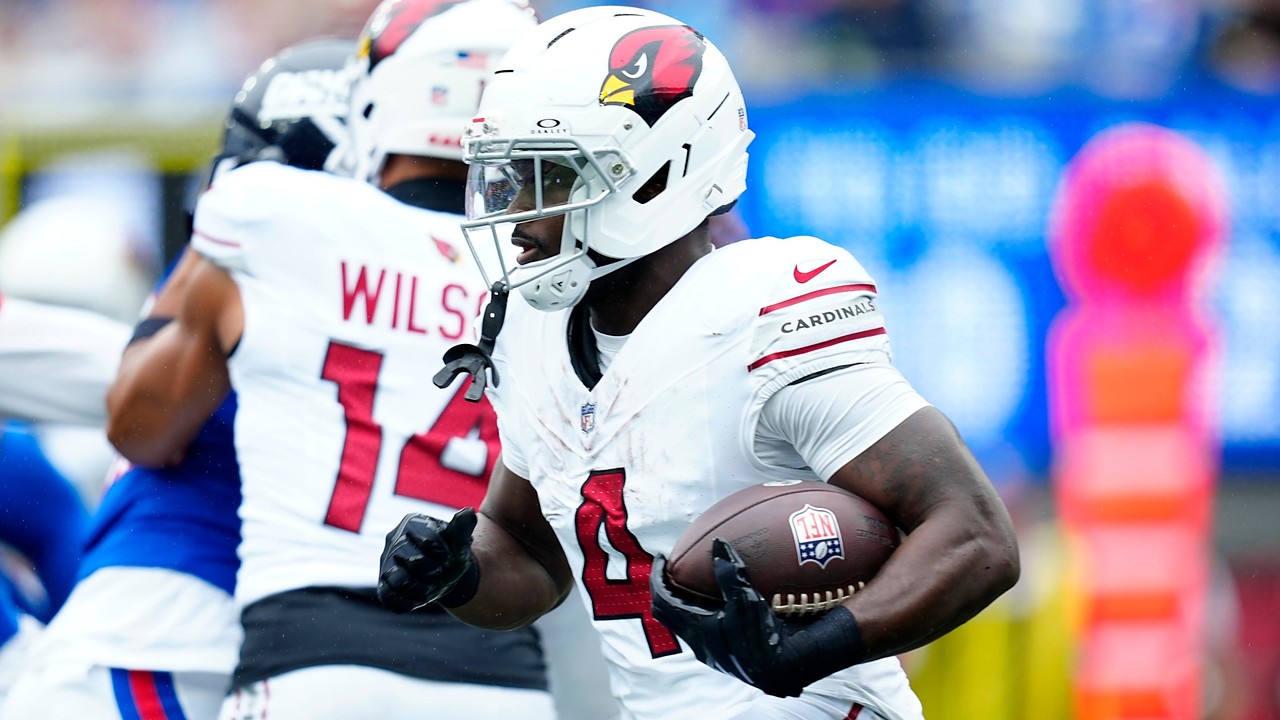 Arizona Cardinals running back Jeremiyah Love tucks the ball under his right arm as he runs upfield past a teammate.
