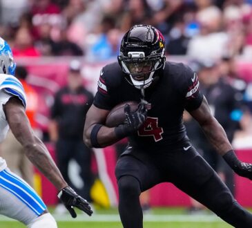 Cardinals running back Jeremiyah Love cuts upfield with the ball as a Lions defender closes in.