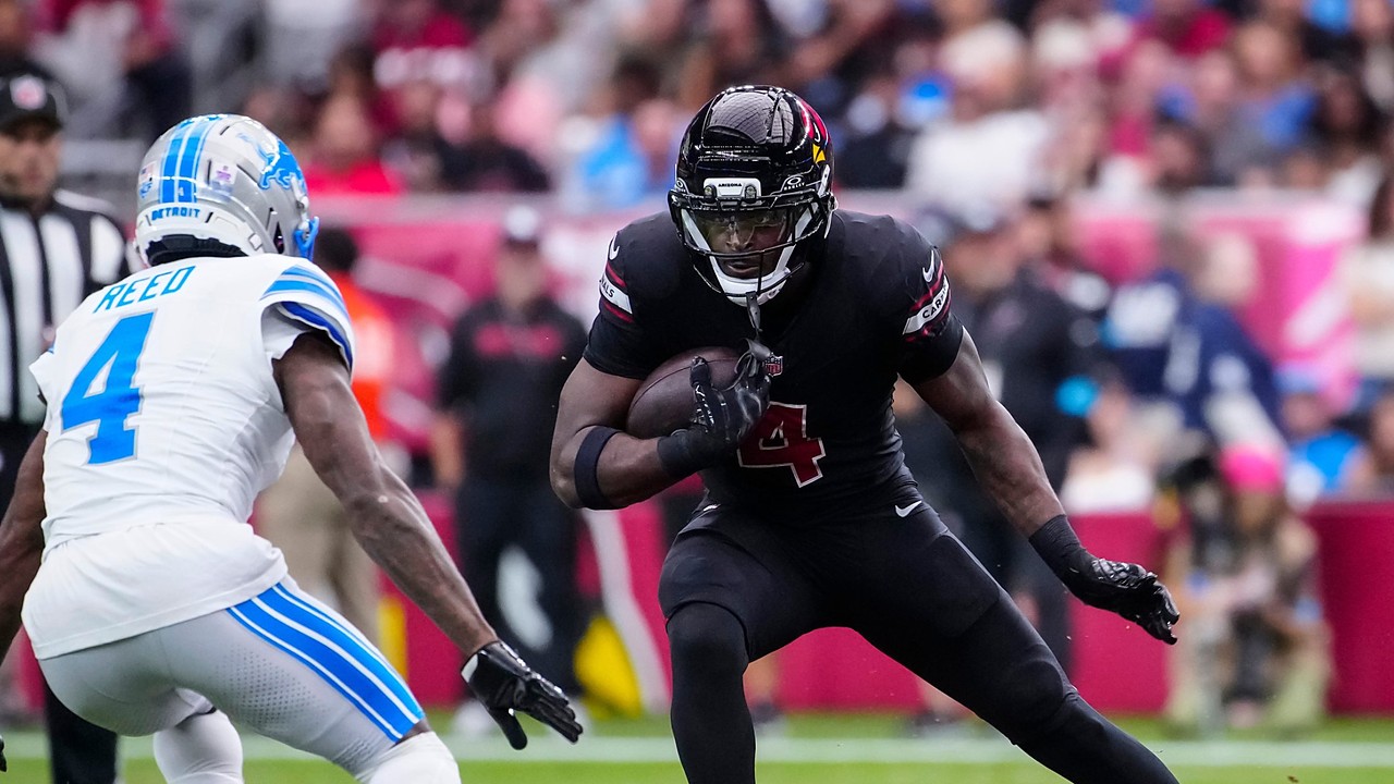 Cardinals running back Jeremiyah Love cuts upfield with the ball as a Lions defender closes in.