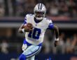Dallas Cowboys quarterback Joe Milton III runs with the ball tucked under his right arm in a white No. 10 jersey.