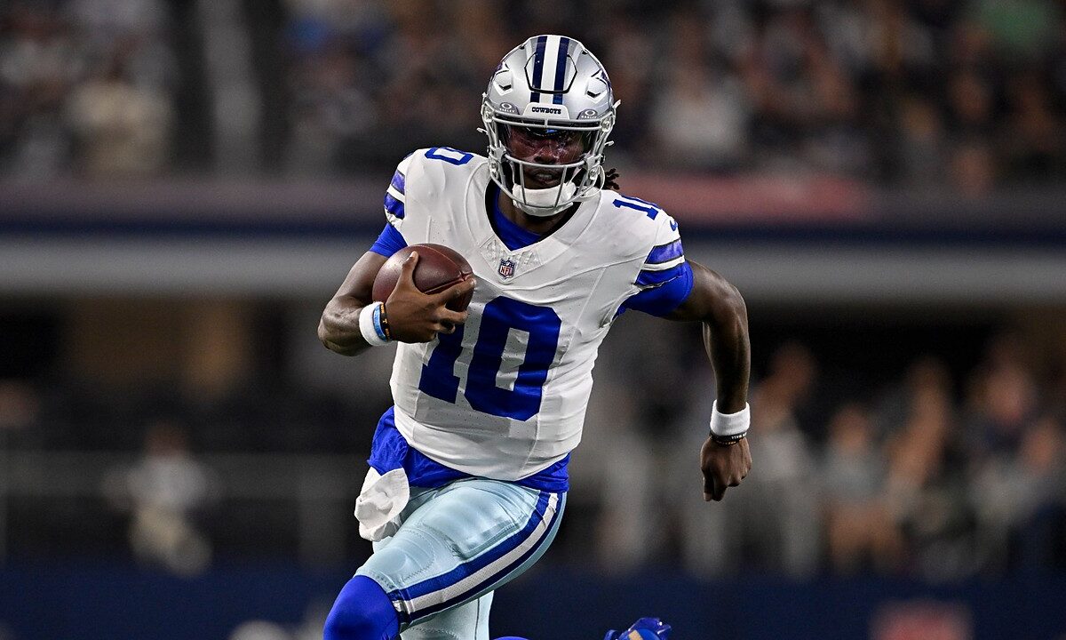 Dallas Cowboys quarterback Joe Milton III runs with the ball tucked under his right arm in a white No. 10 jersey.