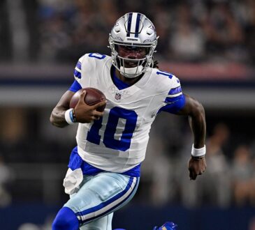 Dallas Cowboys quarterback Joe Milton III runs with the ball tucked under his right arm in a white No. 10 jersey.