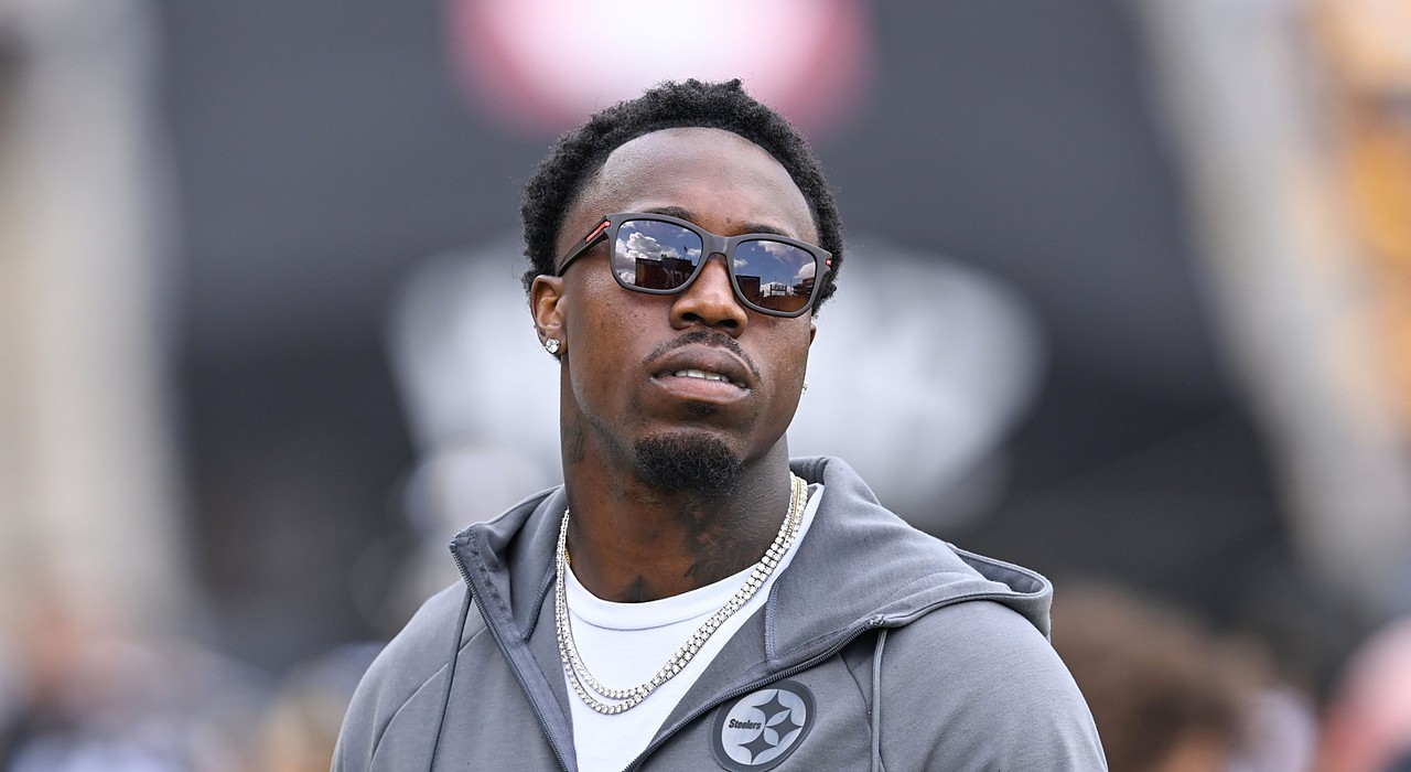 Cornerback Joey Porter Jr., wearing glasses with a black hood pulled over his head, looks on from the field.