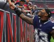 Dallas Cowboys safety Juanyeh Thomas reaches up to shake hands with young fans along the stands after a game.