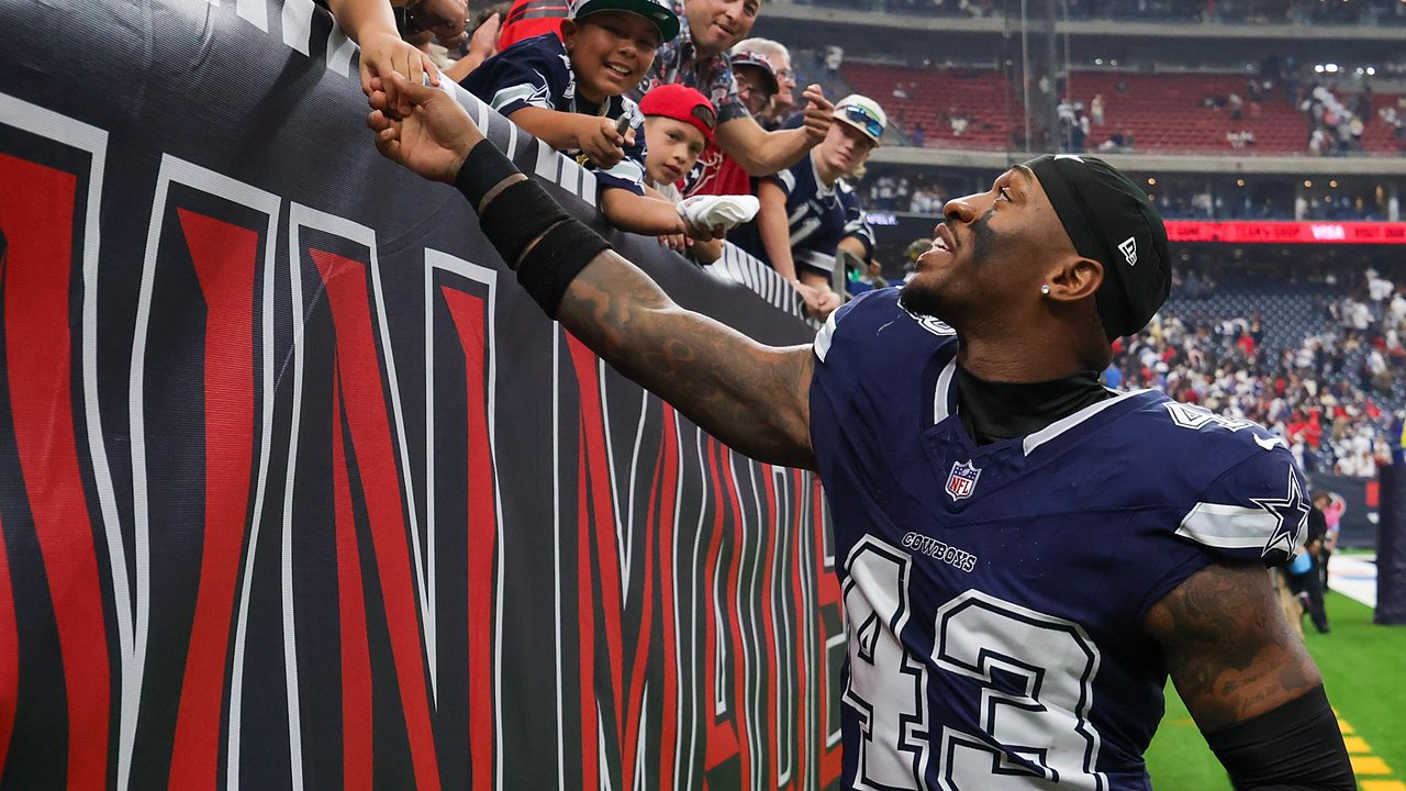 Dallas Cowboys safety Juanyeh Thomas reaches up to shake hands with young fans along the stands after a game.