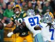 Green Bay Packers quarterback Jordan Love winces as Dallas Cowboys defensive tackle Kenny Clark hits him while he holds the ball.