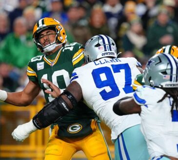 Green Bay Packers quarterback Jordan Love winces as Dallas Cowboys defensive tackle Kenny Clark hits him while he holds the ball.