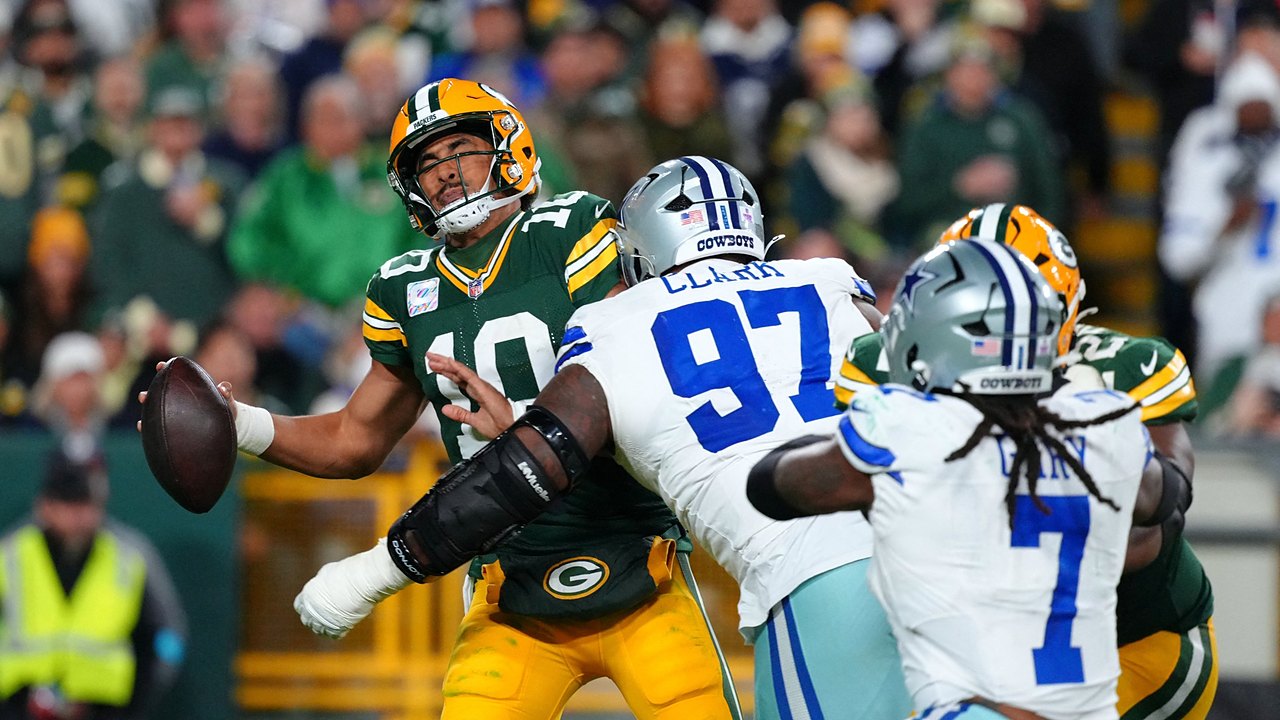 Green Bay Packers quarterback Jordan Love winces as Dallas Cowboys defensive tackle Kenny Clark hits him while he holds the ball.