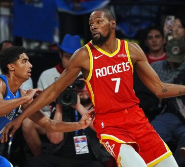 Rockets forward Kevin Durant holds the ball out wide as Mavericks guard Max Christie reaches in to defend.