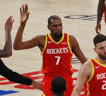 Rockets forward Kevin Durant raises his hand for a high-five from a teammate as they walk off the court.