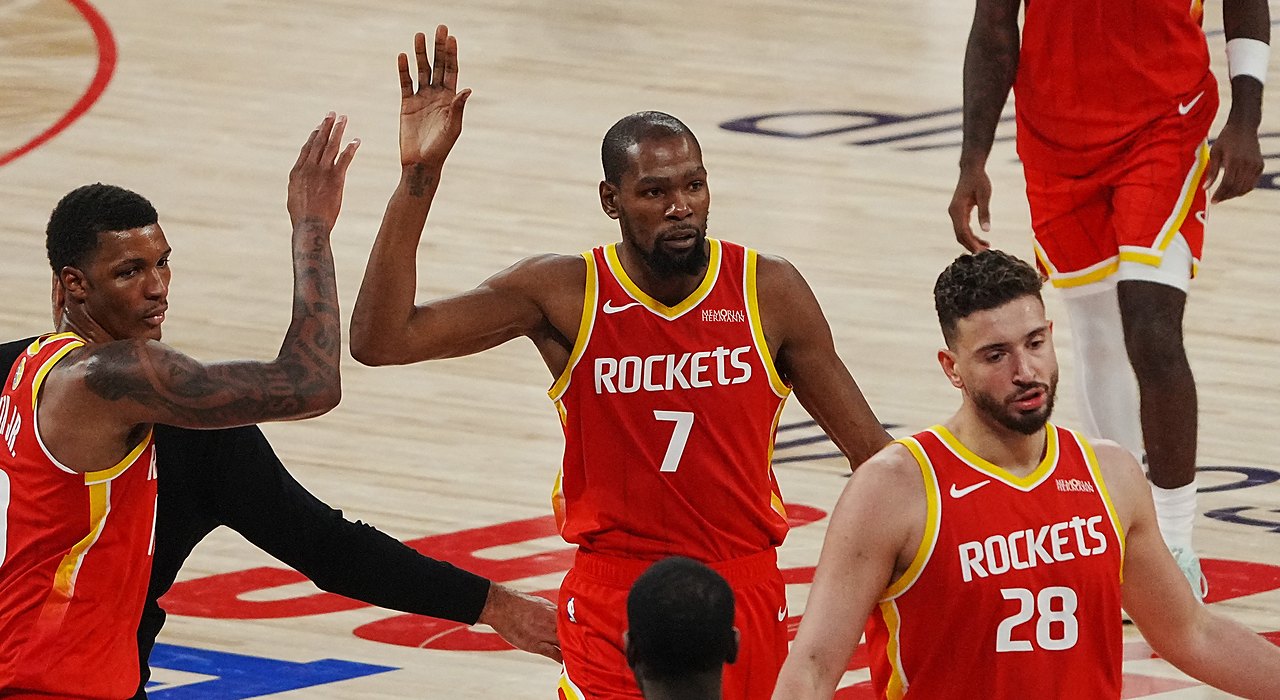 Rockets forward Kevin Durant raises his hand for a high-five from a teammate as they walk off the court.
