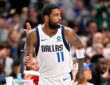 Dallas Mavericks guard Kyrie Irving glances over his shoulder while jogging down the court with his fist clenched.
