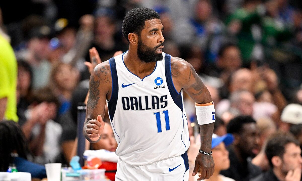 Dallas Mavericks guard Kyrie Irving glances over his shoulder while jogging down the court with his fist clenched.
